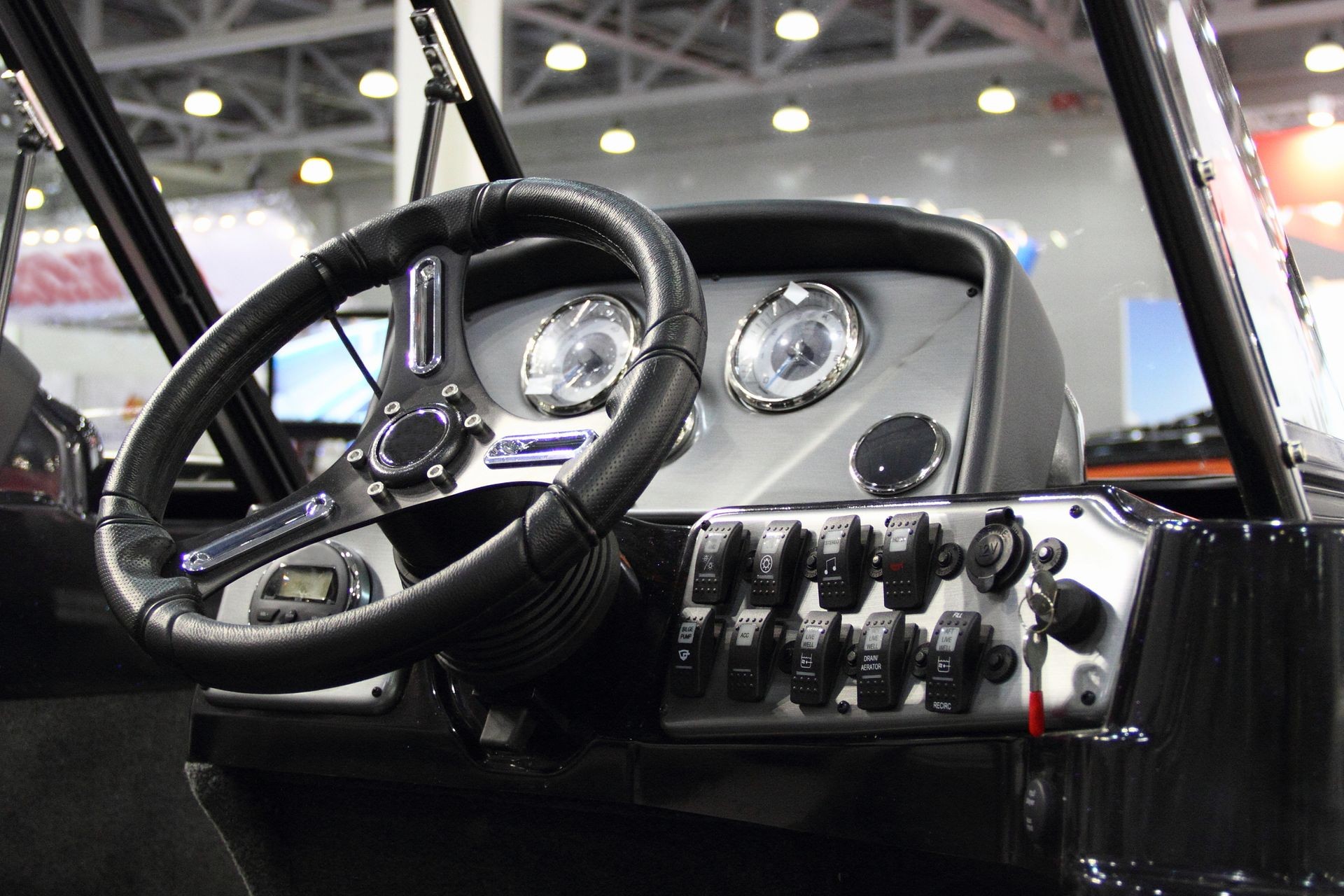 Black plastic steering wheel, control panel and dashboard with switches in the cockpit of the utility motor boat